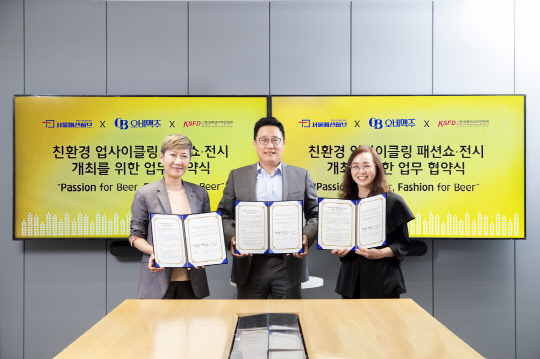 지난 23일 강남구 오비맥주 본사에서 구자범 오비맥주 수석부사장(가운데)과 한국패션디자인학회 회장인 하지수 서울대 교수(왼쪽), 김신우 서울패션허브 배움뜰 센터장이 '친환경 업사이클링 패션쇼·전시' 개최를 위한 업무협약을 맺고 기념촬영을 하고 있다. 오비맥주 제공